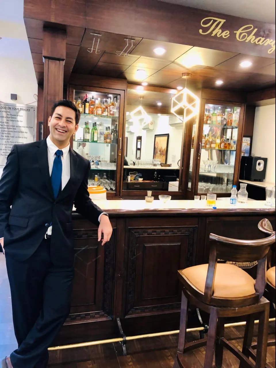Abhay in a suit leaning on a bar