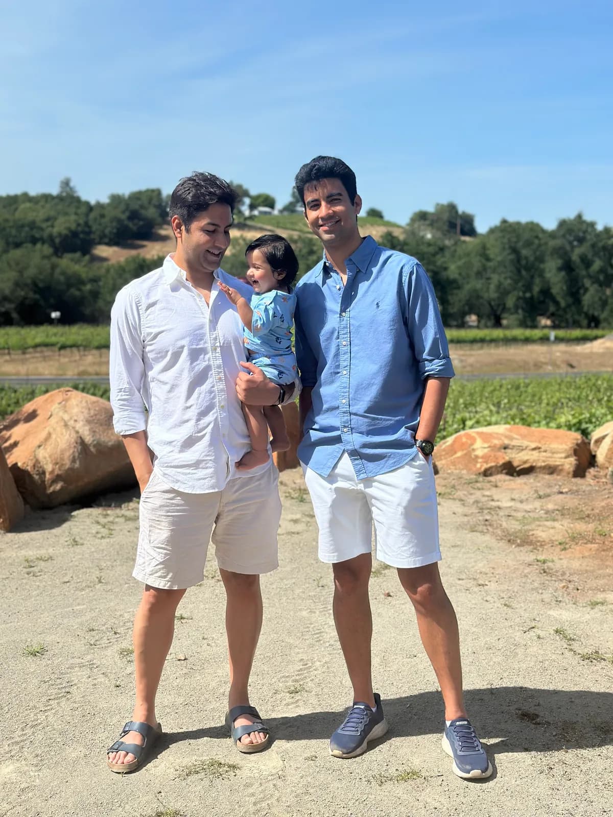 Abhay, a friend and the toddler standing in front of a vineyard